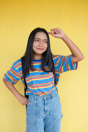 Happy young girl on yellow background, student girl.の写真素材