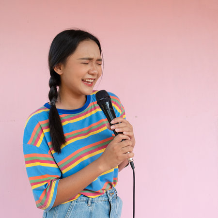 The girl standing and singing music on pink background.の写真素材