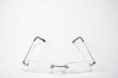 A pair of reading glasses facing front and center of a white frameの写真素材