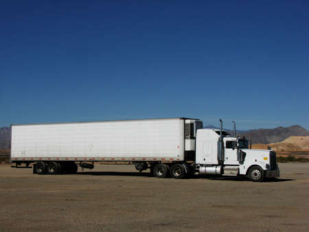 A plain white semi parked in the desert. Features loads of text space.の写真素材