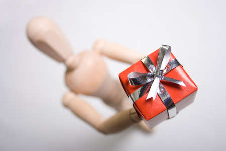 Wooden marionette presenting a red gift. Short DOF.の写真素材