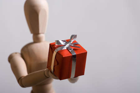 Wooden marionette presenting a red gift. Short DOF.の写真素材