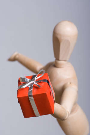 Wooden marionette presenting a red gift. Short DOF.の写真素材