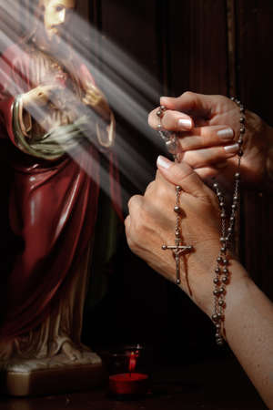 Rosary beads, light rays falling on handsの写真素材