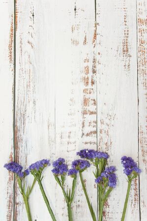 Dried flowers on a light wooden background. Purple flowers on the edge of the table. Background for...
