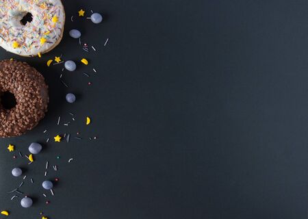 Sweet donuts on a black background with chocolate and berries.
