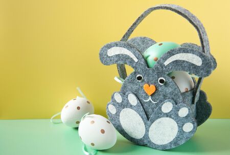 Eggs with rabbits figurines on a bright background. Spotted eggs. Several objects. Healthy food. Easter holiday. Bunny basket for eggs. Easter decoration.の写真素材