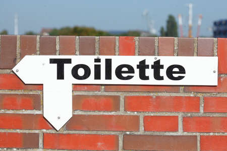 Toilet Sign with Arrow on a Brick Wallの写真素材