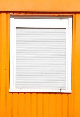 Windows with closed shutters on an orange Container