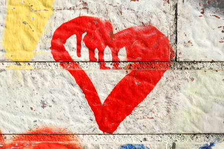 red heart painted on a white brick wallの写真素材