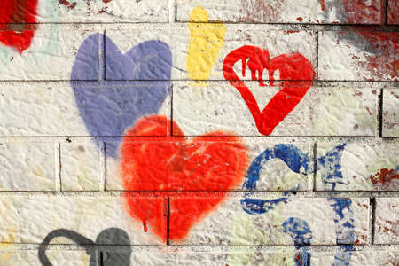 colorful hearts painted on a white brick wallの写真素材