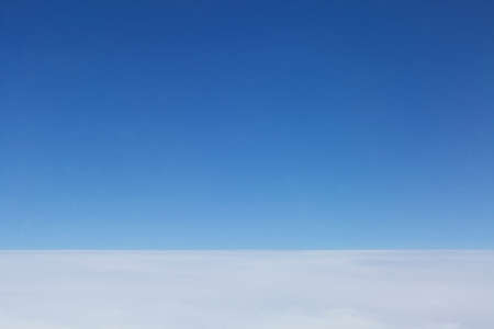 Blue sky, horizon, closed cloud cover seen from above from an airplane, aerial view
