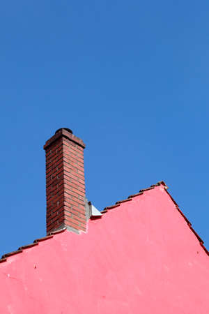 Roof, chimney, pink house wall, roof edge, blue skyの写真素材