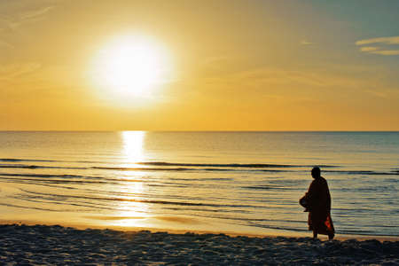 Monks walking in sunrise beach の写真素材