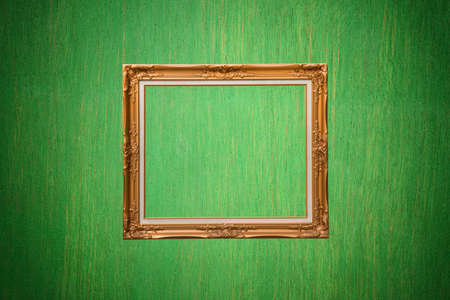 Gold photo frame on green wallの写真素材