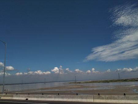 highway in the sea with blue sky and white clouds in the background