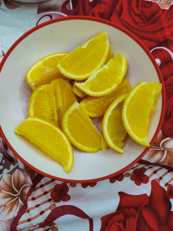 Slices of orange in a plate on a red tableclothの写真素材