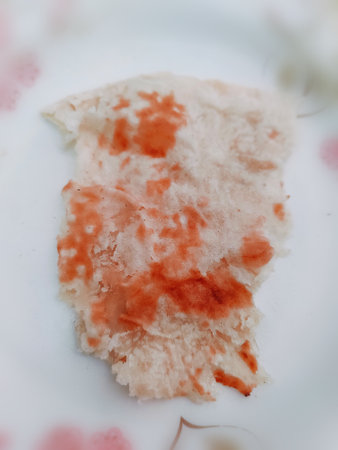 Sticky rice cake in white dish with red and orange stain.
