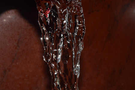 Water splash with drops of water flowing down on a brown background.の写真素材