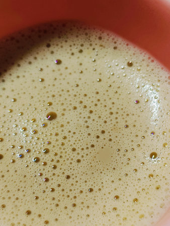 Coffee in a red cup with bubbles, close-up