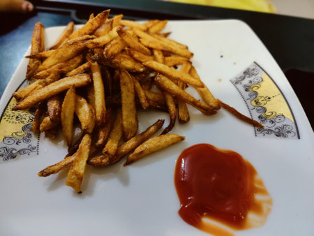 French fries with ketchup on a white plate, close-up
