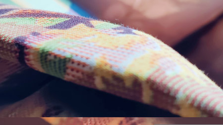 Close-up of a woman's hand embroidering a colorful blanketの写真素材