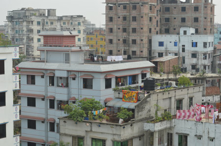Overlooking a residential neighborhood, showcasing lush trees, small houses, and nearby city structures contrasting urban life with natural surroundings.の写真素材