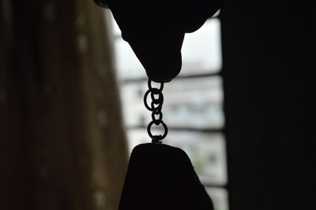 Close-up of a chain hanging on a metal chain with a dark backgroundの写真素材