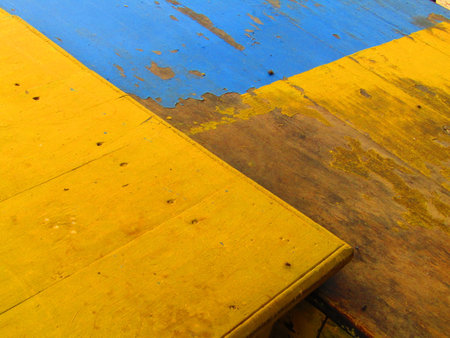 Old wood floor with yellow and blue paint, closeup of photoの写真素材