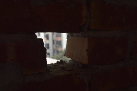 Moody architectural detail of a cracked concrete beam illuminated by a sliver of light inside an...