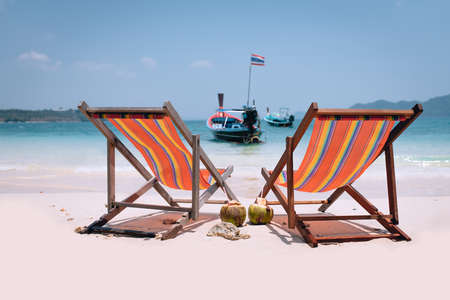 Two beach chairs on perfect tropical white sand and boat in the seaの写真素材