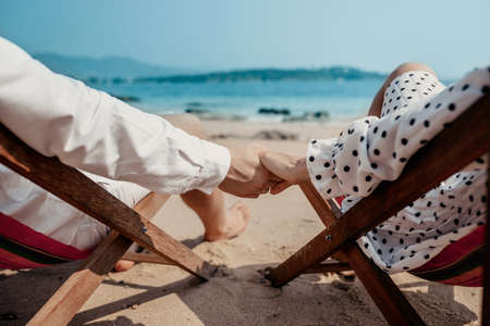 Love - romantic couple holding hands on a beach in sunsetの写真素材