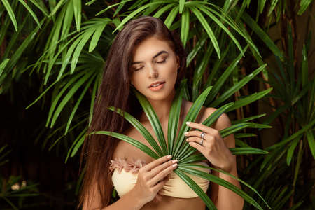 young smiling brunette woman with big green leaf on nature background , spa care people conceptの写真素材