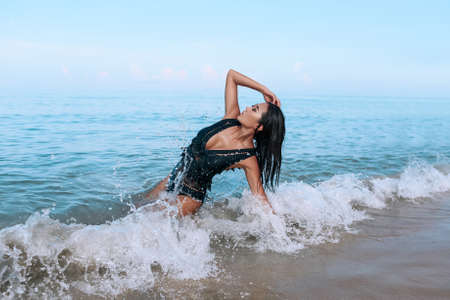 charming miss in a stylish black swimsuit and bright makeup lies and relaxes on the beach.の写真素材