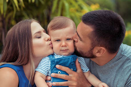 Funny portrait of a happy family. Parents are kissing their son and embracing him.の写真素材