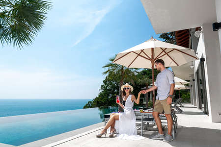 Couple tasting tropical drinks while sitting on sun lounger
