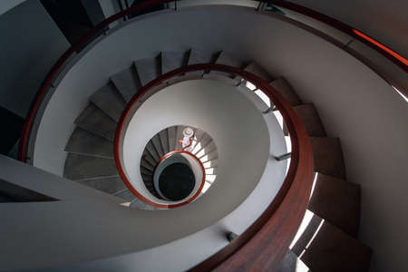 A luxurious girl in a white dress and white hat descends down a white spiral staircase
