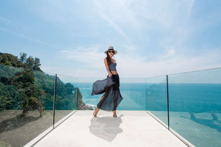 A young woman with slim long legs posing on a glass terraceの写真素材