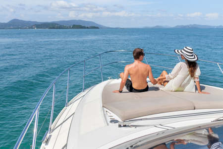Rear view: man and woman sunbathe on a luxury white yacht.の写真素材