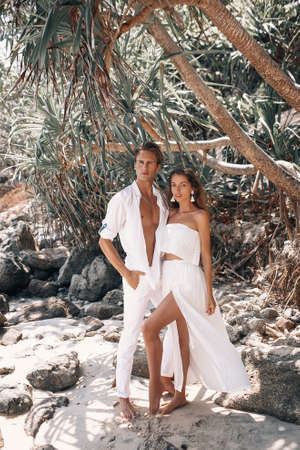 A couple in white clothes is resting on the beach of a wonderful islandの写真素材