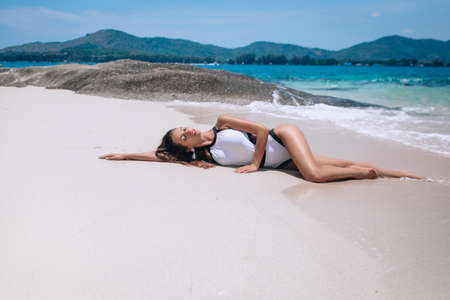 Nice model female in bathing suit l sunbathes on deserted beach.の写真素材