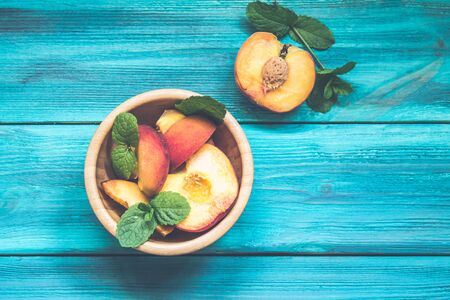 Peaches in a plate on a wooden background.