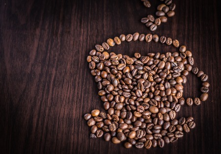 Roasted coffee beans placed in the shape of a cup and saucer.の写真素材