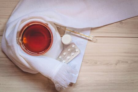 Hot tea for colds, pills on table close-up.の写真素材