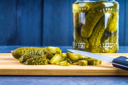 Cucumbers or pickled gherkins with a knife on a wooden cutting board. Blue gray background. Bank with cucumbersの写真素材