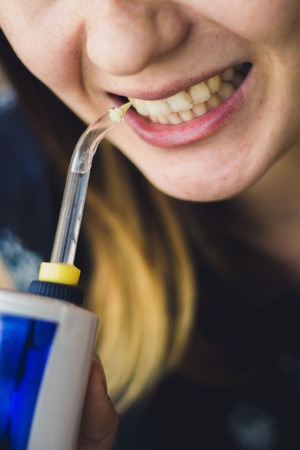 A woman using an oral irrigator in bathroom.の写真素材
