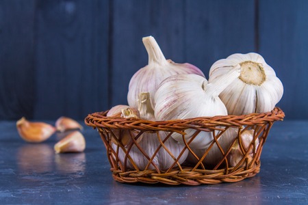 Garlic cloves and garlic bulb on a wooden board on a gray backgroundの写真素材