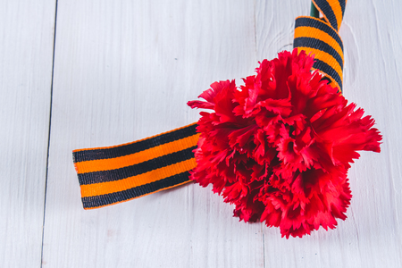 Red carnations tied with Saint George ribbon on gray.の写真素材