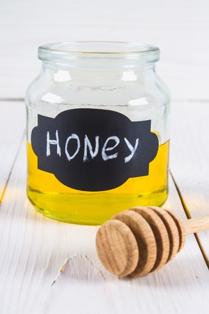 Mead jar labeled honey with a dripper, on a white tableの写真素材