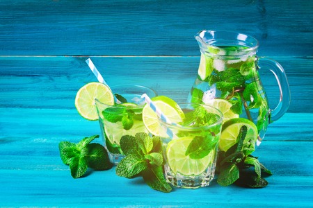 Mojito with mint and lime in a glass and a jug with tubes. Blue wood backgroundの写真素材
